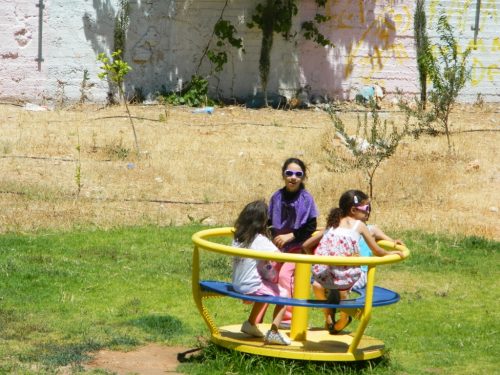 Some of our summer campers on the merry go round in Wi'am's yard