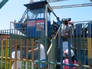 Some excited young patrons board the giant swinging ride.